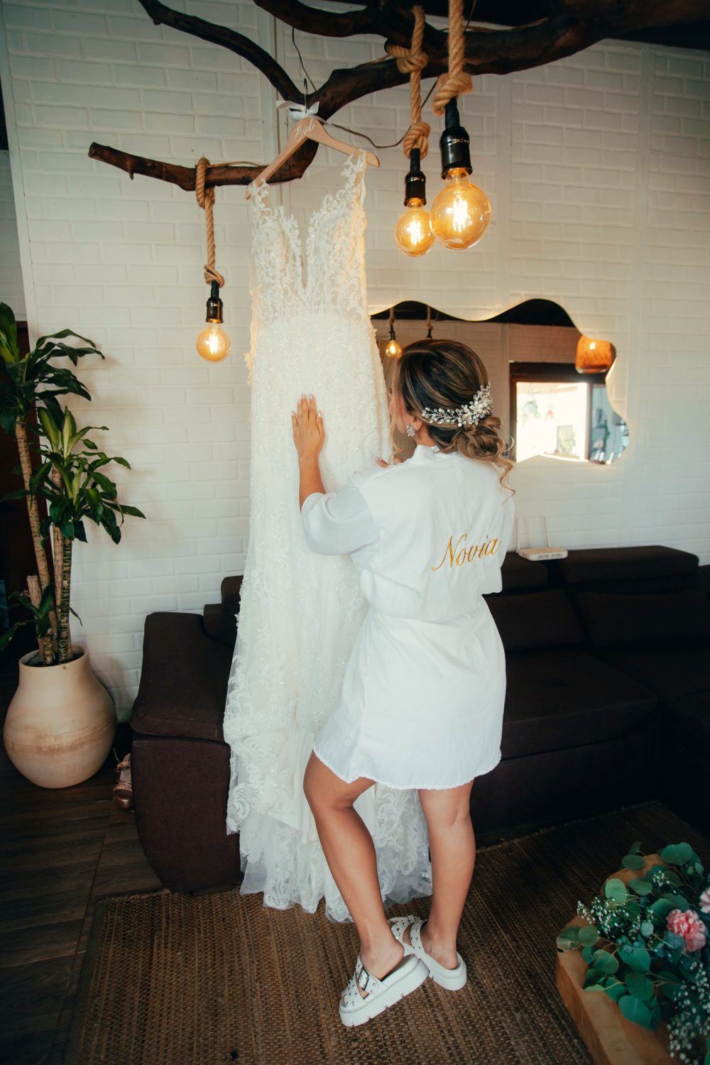 La novia junto a su vestido colgado de una rama con bombillas